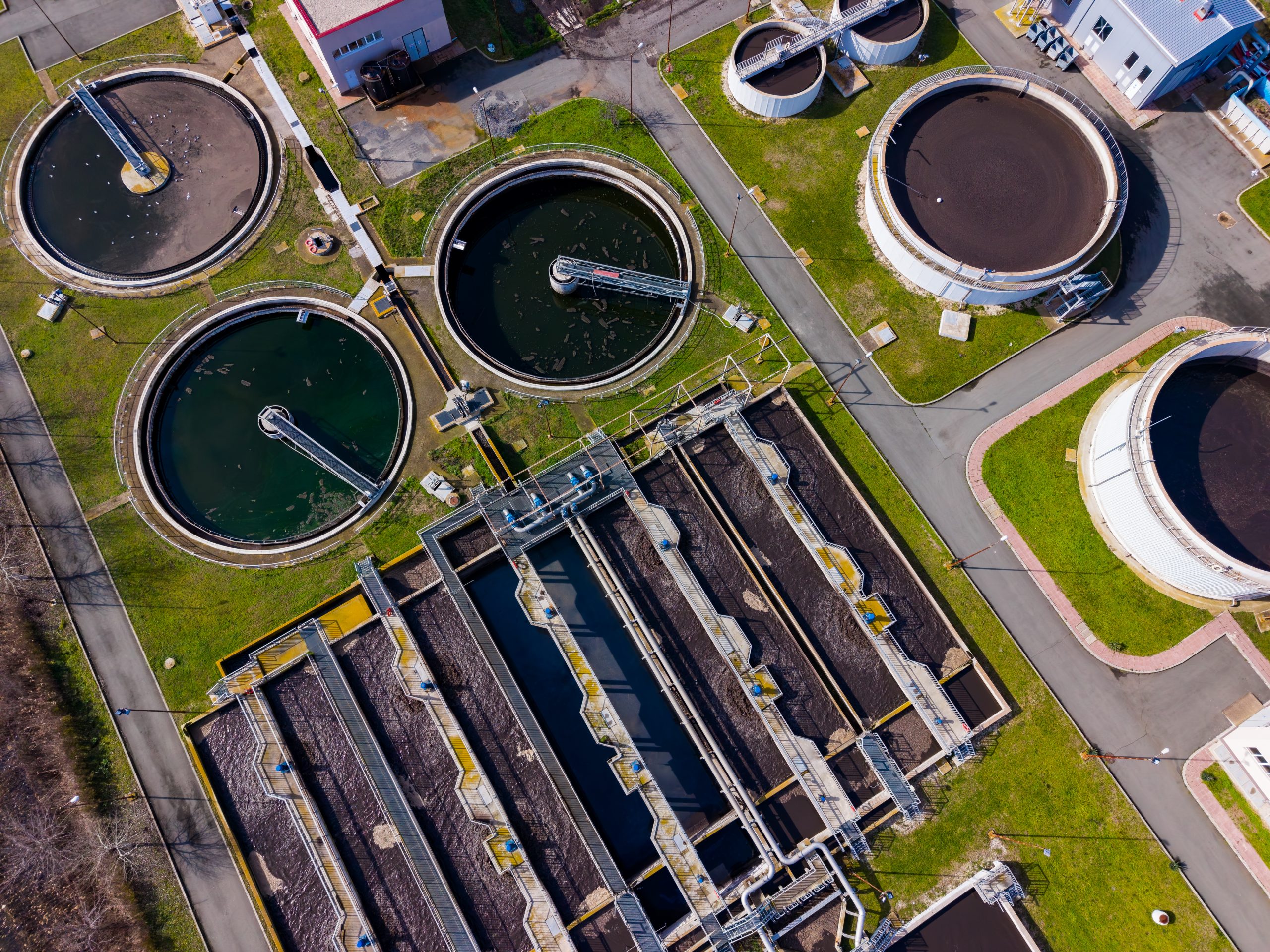 Wastewater treatment plant in operation with multiple tanks and processing areas during daytime
